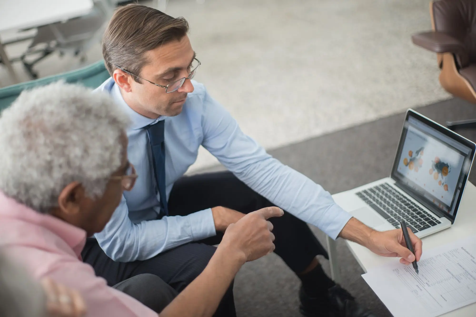 Company director and his accountant going through cash flow figures on a laptop and printed reports to check whether the business can pay its debts on time