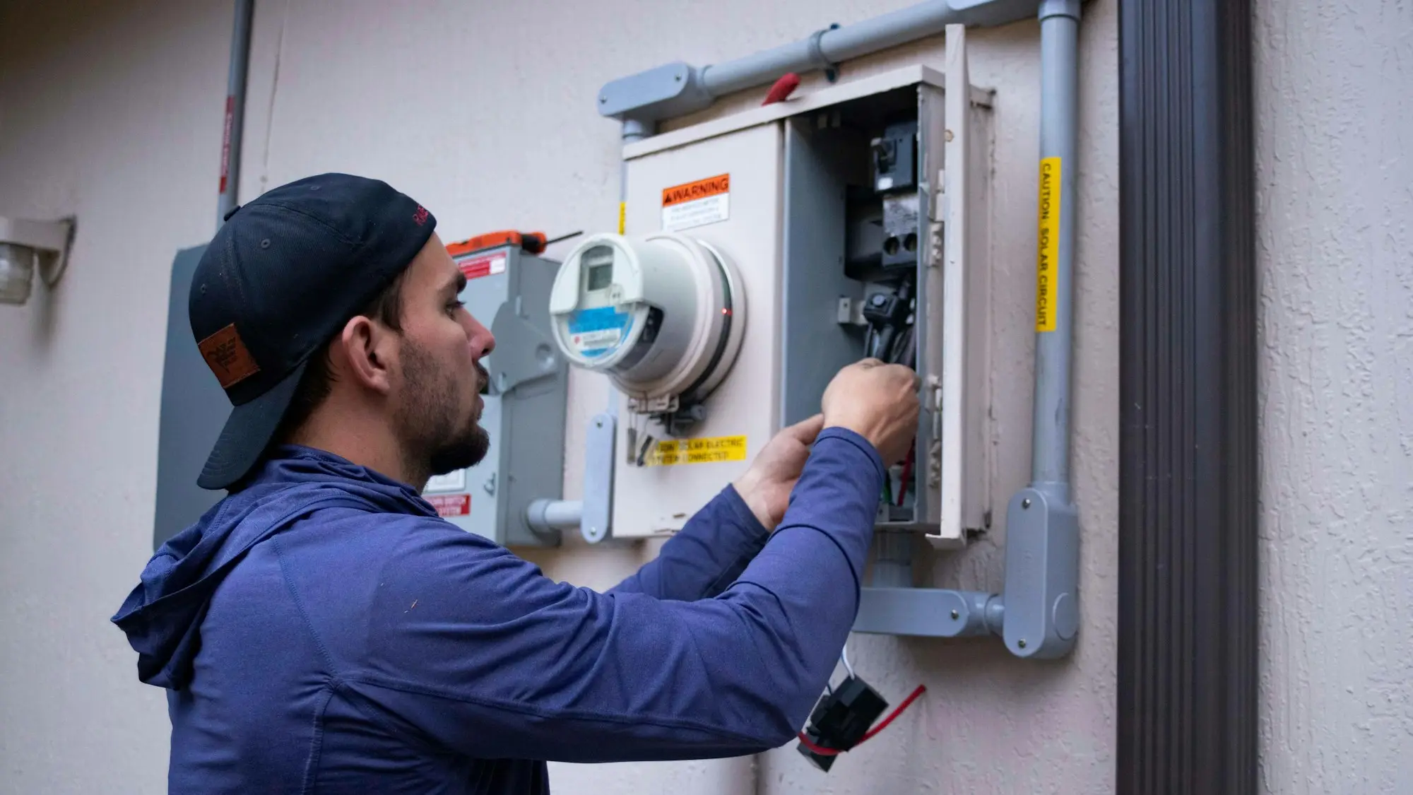 Sole trader electrician working on a switchboard meter box on a job site